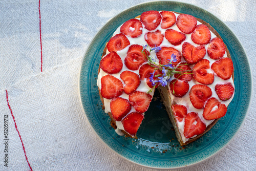 Cake with strawberries and cream on blue plate. Summer Strawberry and Cream sponge Layer Cake on white table cloth background. Top view, copy space. Midsummer food dessert