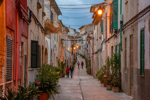 People in street in narrow street at dusk in the old town of Alcudia, Alcudia, Majorca, Balearic Islands photo