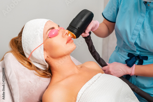 Beautician in pink gloves removes the mustache from the client's woman's face. Close up. The concept of laser hair removal