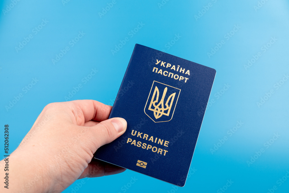 Passport of a citizen of Ukraine in a female hand on a blue background, close-up. Inscription in Ukrainian Ukraine Passport Passport of a citizen of Ukraine in a female hand on a blue background, close-up. Inscription in Ukrainian Ukraine Passport
