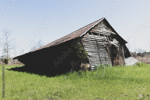 Abandoned barn leaning and near to collapse in a field. photo