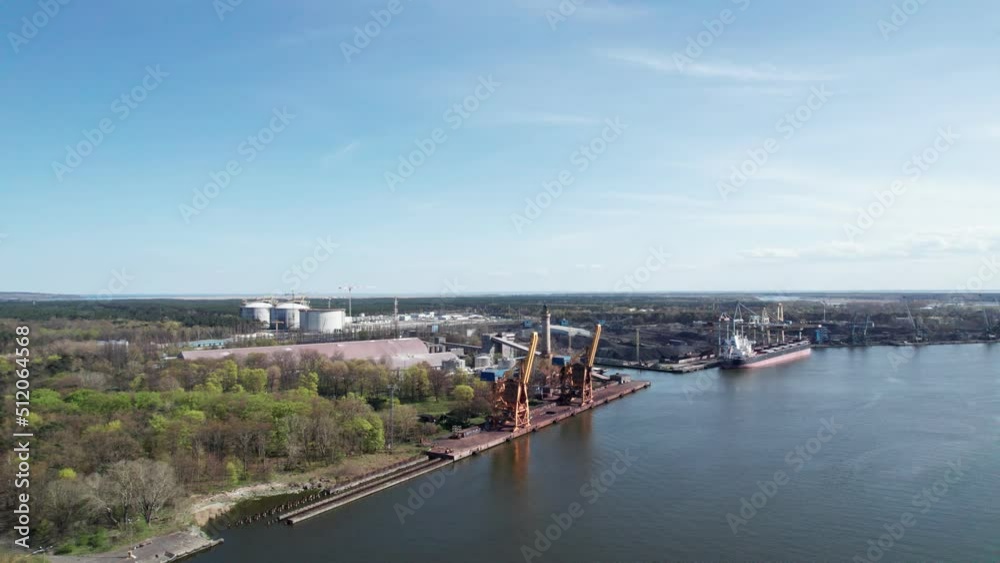 Aerial view of a cargo ship being unloaded by huge cranes in a port. Transport of loose mineral resources. Aerial view of a cargo ship being unloaded by huge cranes in a port. Transport of loose mineral resources.