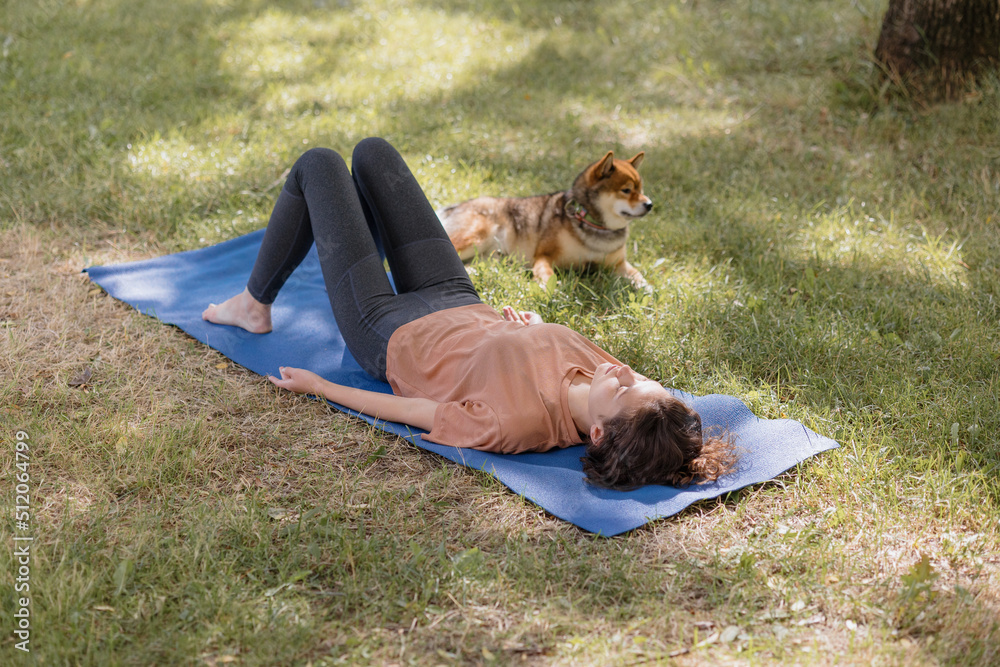 a European woman with meditates in the park with her dog on a blue