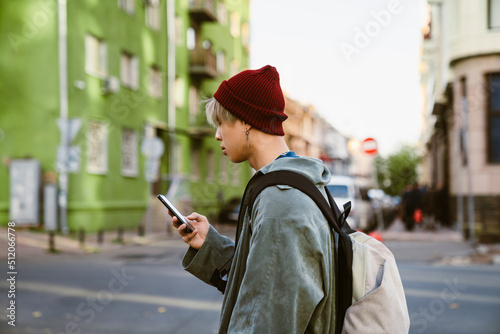 Asian boy using mobile phone while walking on city street