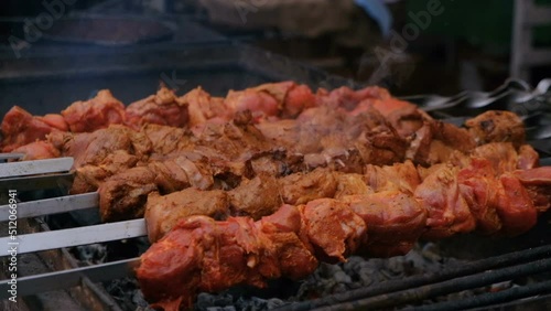 Roasting juicy meat steak with spices and herbs in burning charcoals fire on bbq grid, flames and smoke in slow motion. Juicy steak with grilling stripes ready for picnic celebration. Barbecue grill