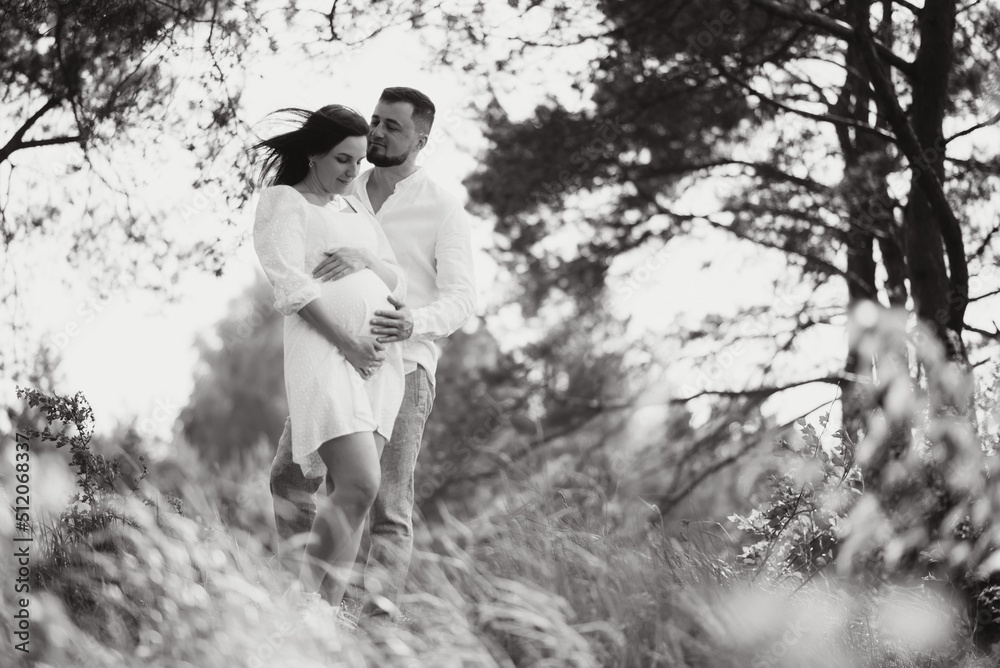 Happy and young pregnant couple hugging in nature Happy and young pregnant couple hugging in nature