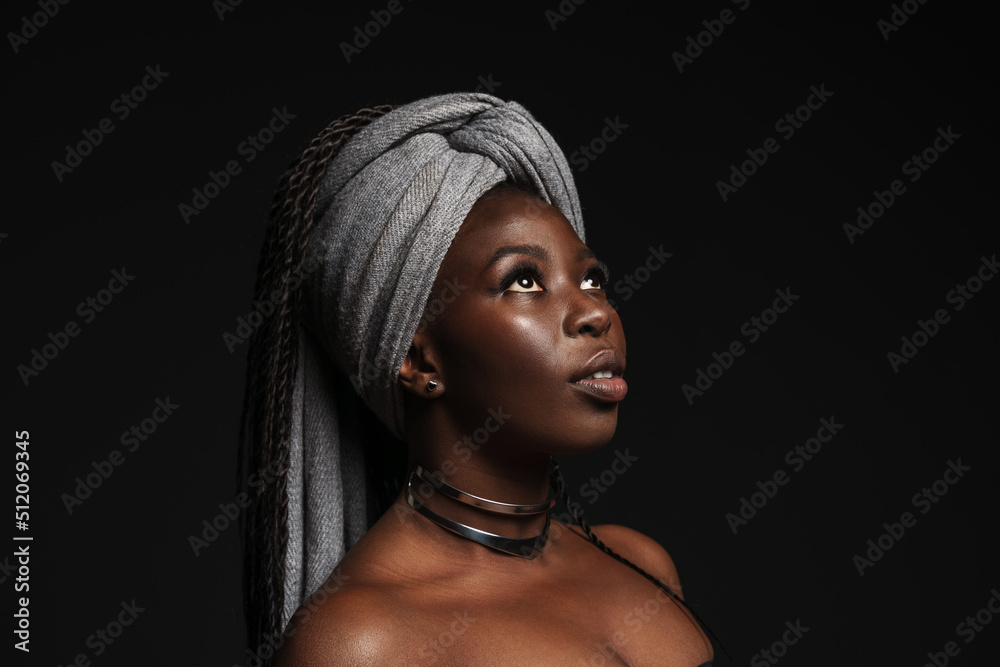 Shirtless black woman wearing headscarf looking downward