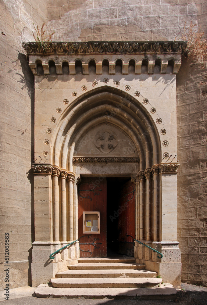 Pointed gothic arch with ancient wooden door at St Vincent church in the old town of Fabrezan in Aude, Occitanie region in France