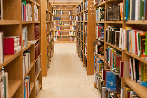 Wooden library shelves with books. Bookshelves with stacks of books. Bookstore or university or library.