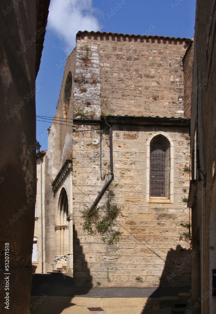 Narrow alley with the church of St Vincent in the old town of Fabrezan in Aude, Occitanie region in France