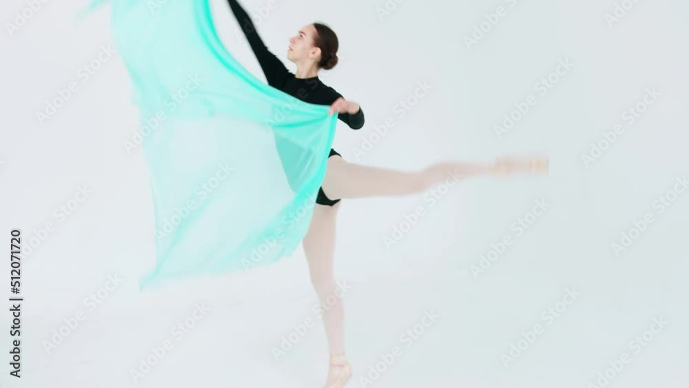 A graceful ballerina in a black leotard performs a fouette and an attitude with a fluttering turquoise veil in her hands A graceful ballerina in a black leotard performs a fouette and an attitude with a fluttering turquoise veil in her hands