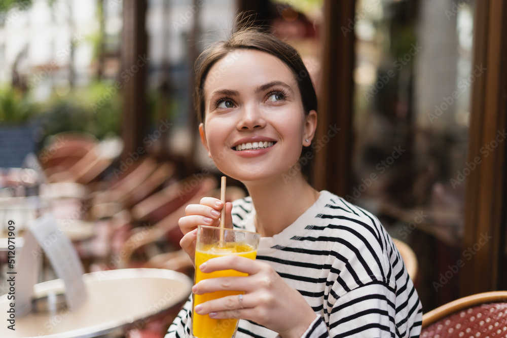 happy woman in striped long sleeve shirt holding glass of fresh orange juice in outdoor cafe in paris. happy woman in striped long sleeve shirt holding glass of fresh orange juice in outdoor cafe in paris.