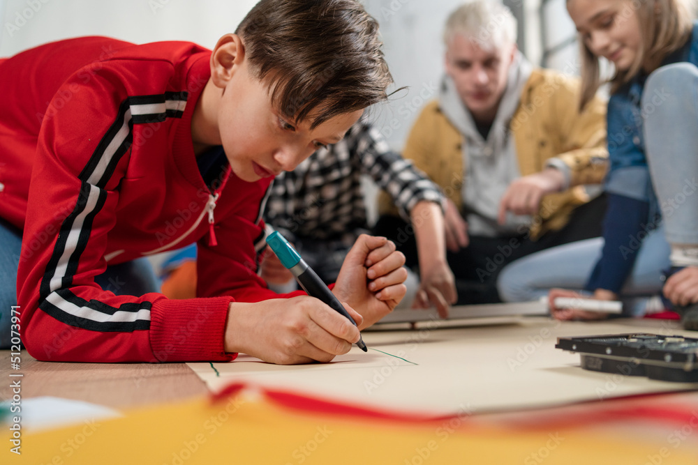 Kids with teacher working together on project with electric toys and robots at robotics classroom Kids with teacher working together on project with electric toys and robots at robotics classroom