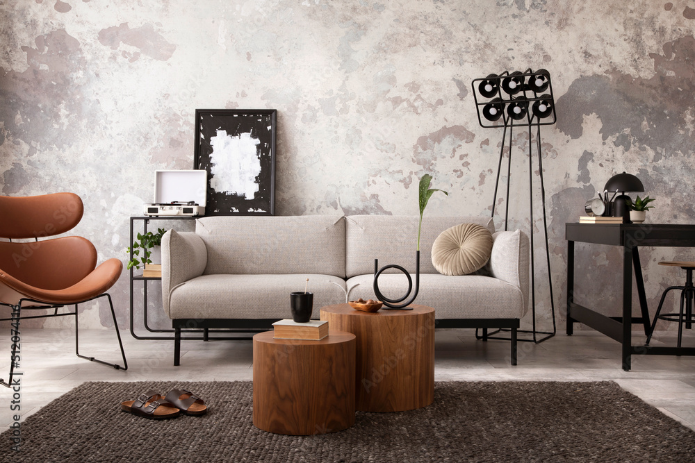 The stylish compostion at living room interior with design gray sofa,  wooden coffee table, desk and elegant personal accessories. Loft and  industrial interior. Home decor. Template. . Photos | Adobe Stock
