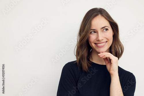 Beautiful portrait of young happy woman with a big smile on her face. Looking cute to the right, standing isolated on white background with copyspace.