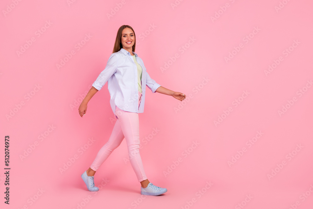 Full size profile photo of gorgeous satisfied lady walking toothy smile isolated on pink color background