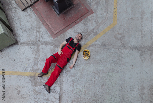Top view of worker lying on floor after accident in factory. First aid support on workplace concept.
