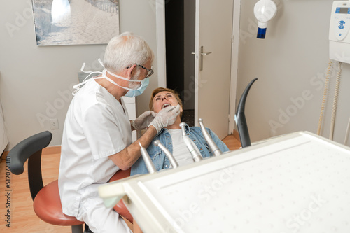 Mature experienced male doctor in glasses and face mask performs a regular examination of the patient. Doctoral practice. Patient healthcare