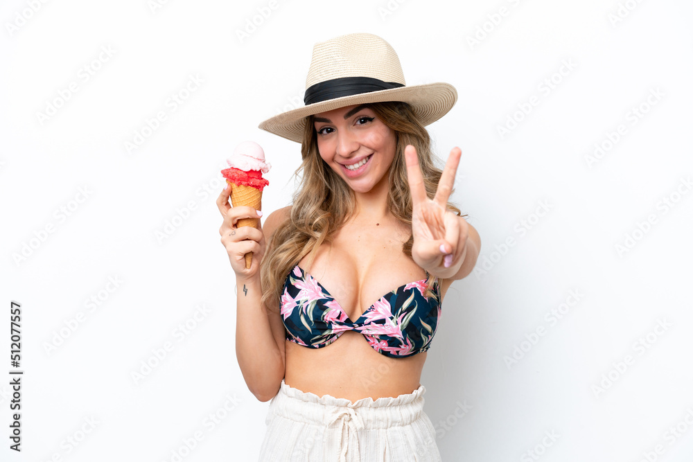 Girl wearing a swimsuit and holding cornet ice cream isolated on white background smiling and showing victory sign Girl wearing a swimsuit and holding cornet ice cream isolated on white background smiling and showing victory sign