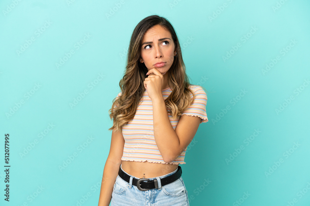 Young woman over isolated blue background having doubts Young woman over isolated blue background having doubts