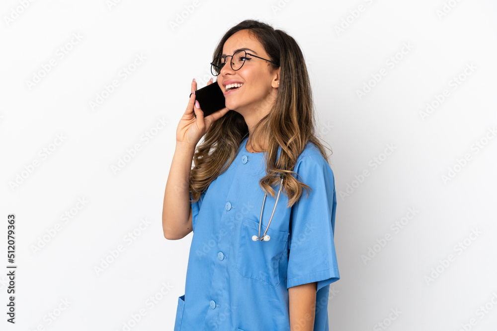 Young surgeon doctor woman over isolated white wall keeping a conversation with the mobile phone Young surgeon doctor woman over isolated white wall keeping a conversation with the mobile phone