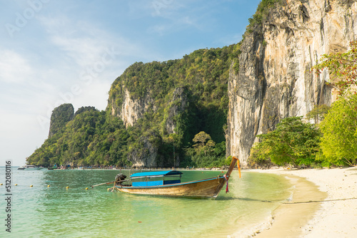 Beach and cliffs on a tropical island with boat docked near the shore