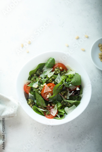 Healthy green salad with tomatoes, pesto and cheese