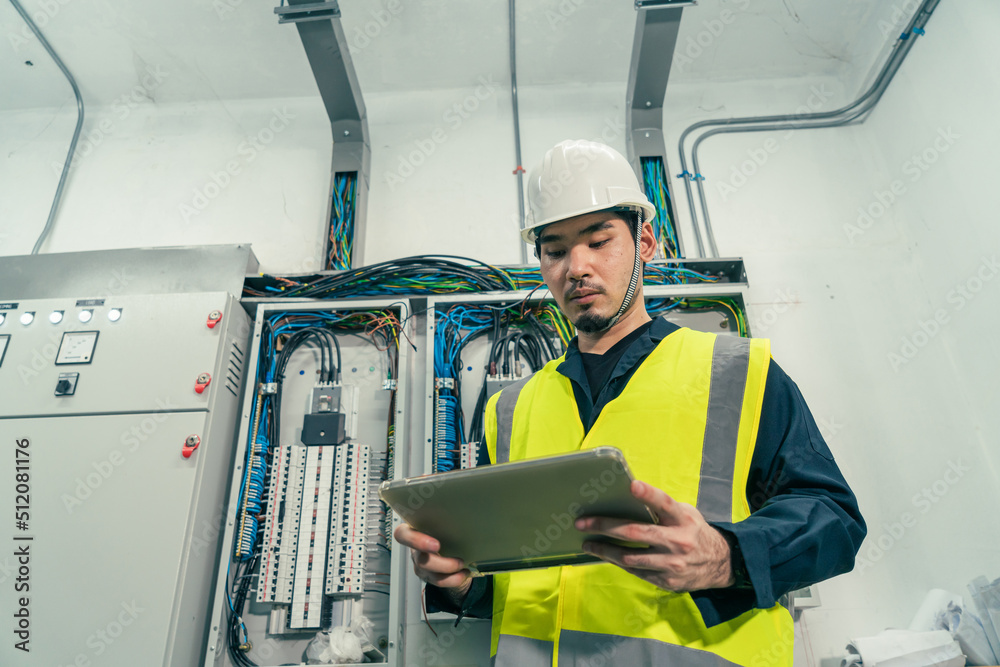 Professional Electrical Engineer or Electrician service working use tablet inspection electrical at control panel room. Maintenance Engineer check or repair electrical control panel. Professional Electrical Engineer or Electrician service working use tablet inspection electrical at control panel room. Maintenance Engineer check or repair electrical control panel.