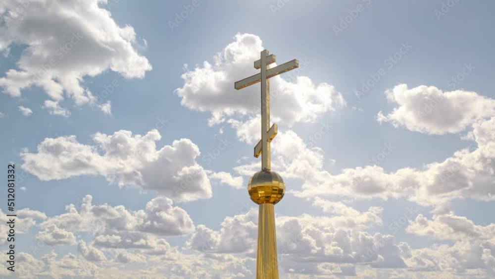 Golden cross against cloudy blue sky. christian crucifix illuminated by sunlight. church Religious symbol of the faith in god made of gold. Aerial view. Golden cross against cloudy blue sky. christian crucifix illuminated by sunlight. church Religious symbol of the faith in god made of gold. Aerial view.