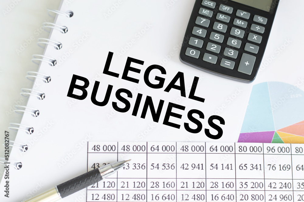 Legal business text on notepad next to pen, calculator and reports Legal business text on notepad next to pen, calculator and reports