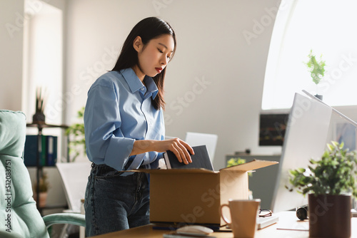 Fired Asian Woman Packing Belongings In Box After Dismissal Indoor