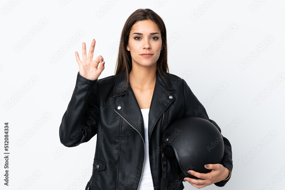 Caucasian girl holding a motorcycle helmet on white background showing an ok sign with fingers Caucasian girl holding a motorcycle helmet on white background showing an ok sign with fingers