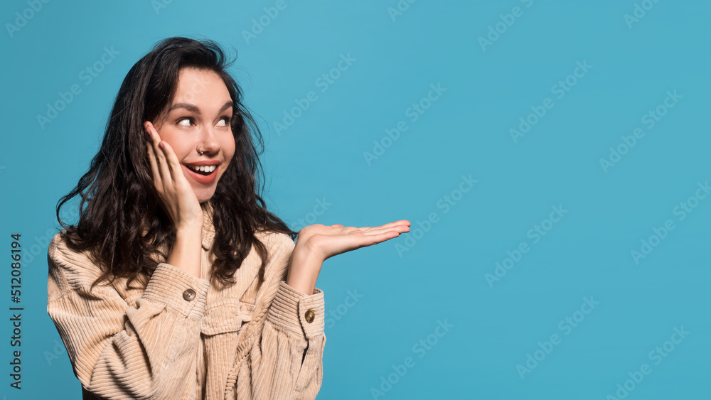 Surprised glad millennial european female brunette student in casual holding empty space on her hand Surprised glad millennial european female brunette student in casual holding empty space on her hand