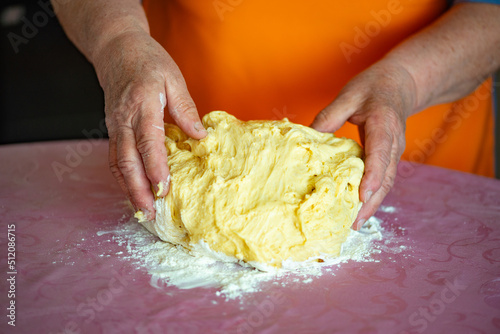 grandmother kneads dough for Easter cakes on the table