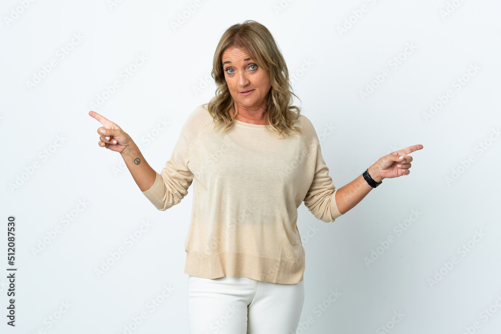 Middle aged blonde woman over isolated white background pointing finger to the laterals and happy Middle aged blonde woman over isolated white background pointing finger to the laterals and happy
