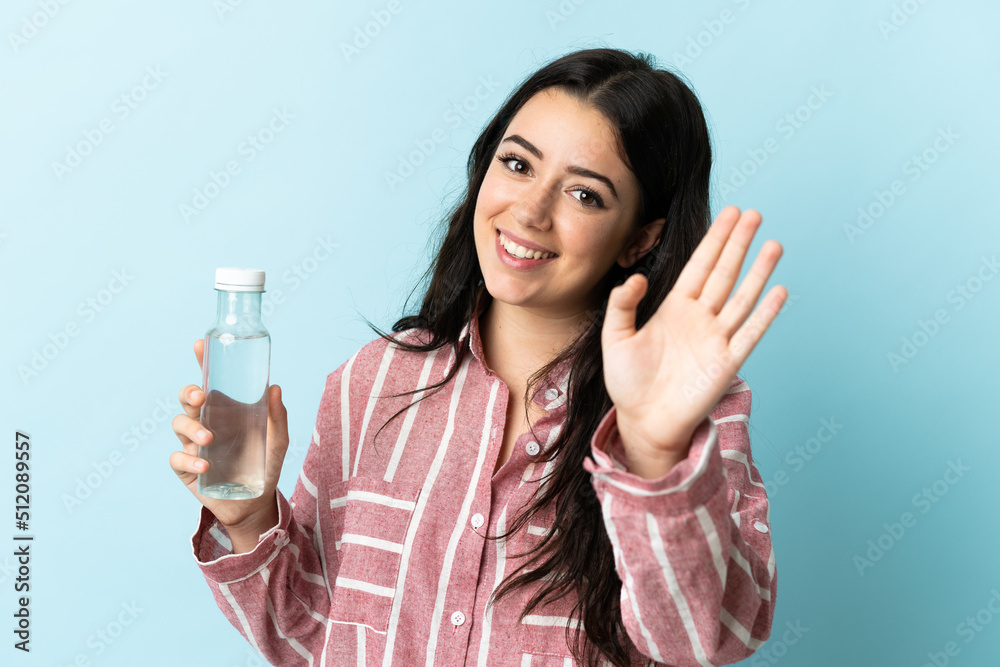 Young woman with a water isolated on blue background saluting with hand with happy expression Young woman with a water isolated on blue background saluting with hand with happy expression