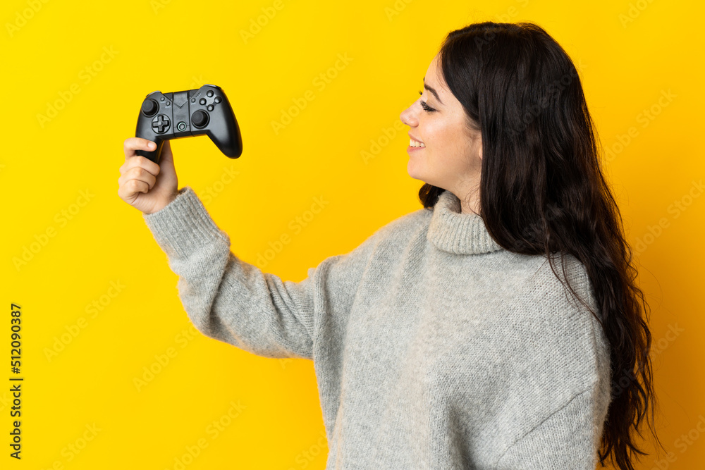 Woman playing with a video game controllerisolrted on yellow background with happy expression Woman playing with a video game controllerisolrted on yellow background with happy expression