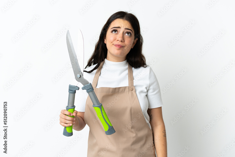 Young caucasian woman holding a plant isolated on white background and looking up Young caucasian woman holding a plant isolated on white background and looking up