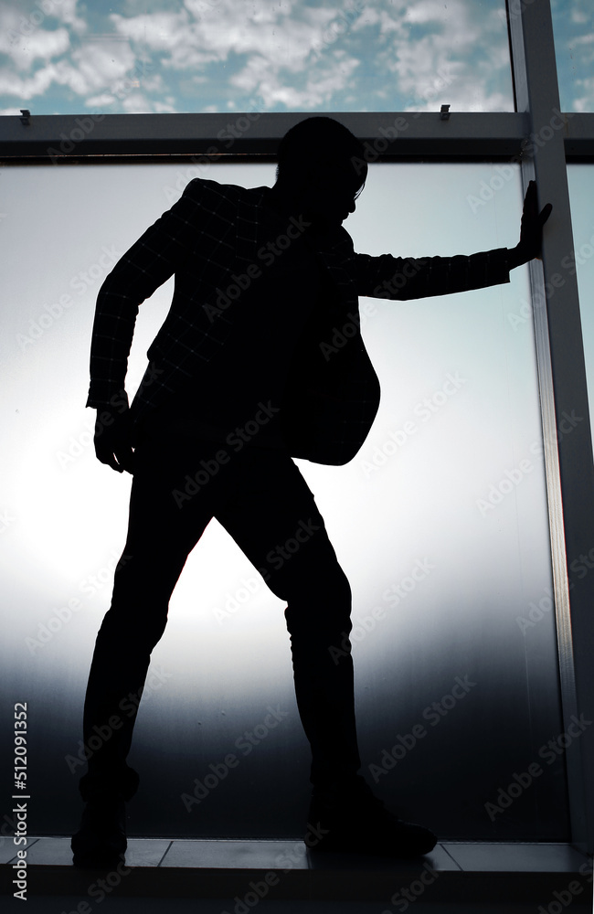 silhouette of a businessman standing near the office window