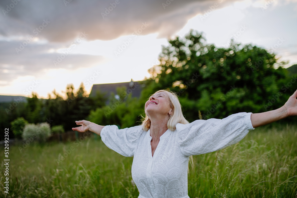 Senior woman with arms outstretched and face up at park on summer day, mental health concept. Senior woman with arms outstretched and face up at park on summer day, mental health concept.