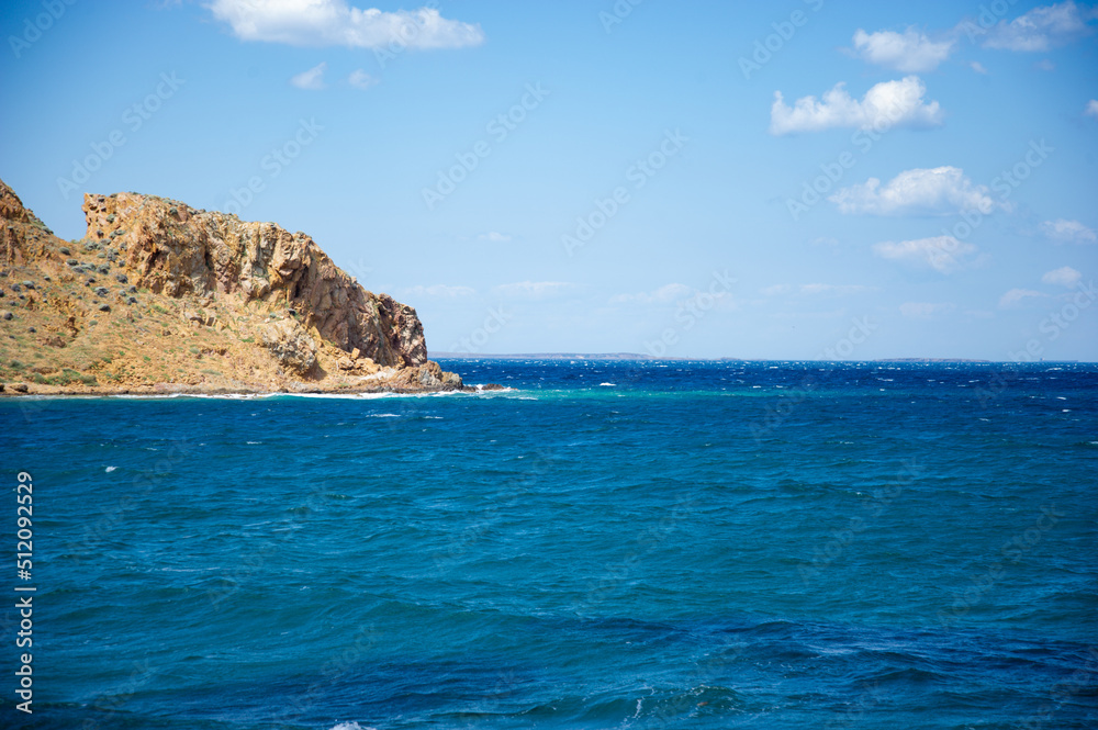 Blue sunny sky, an island in the sea and underwater sandy rocky sea view. Tenedos island beach
