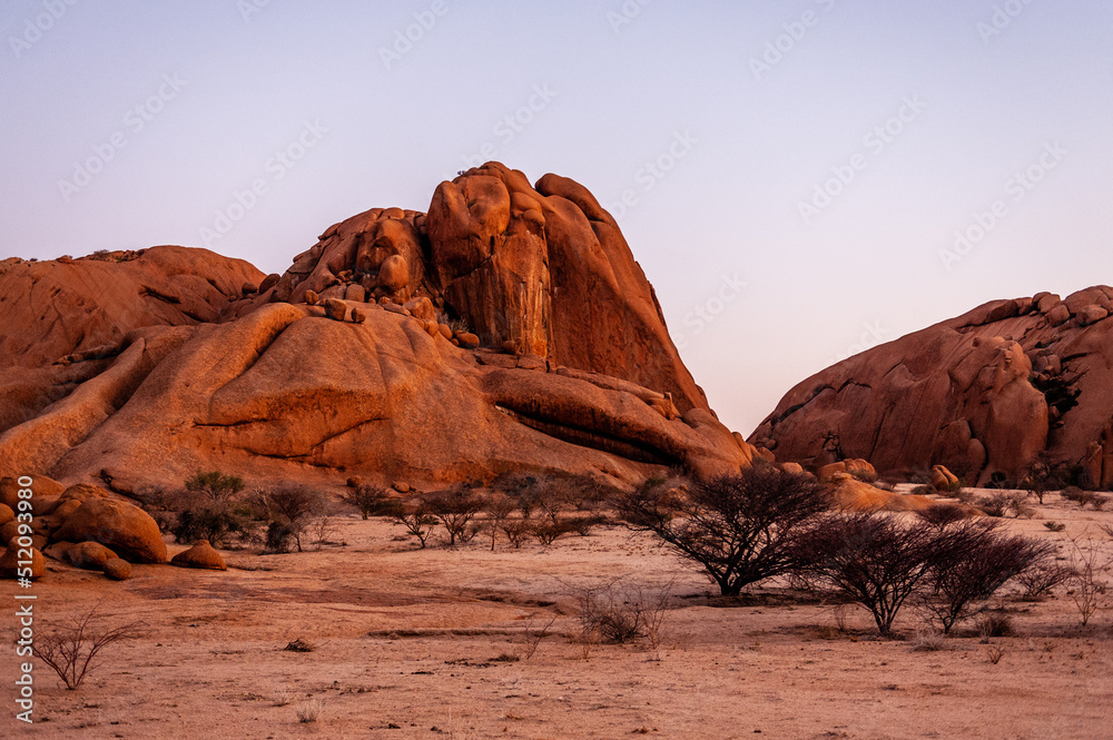 Fototapeta premium Bold rock formations glowing bright orange in the last rays of the setting sun. Spitzkoppe, Namibia.