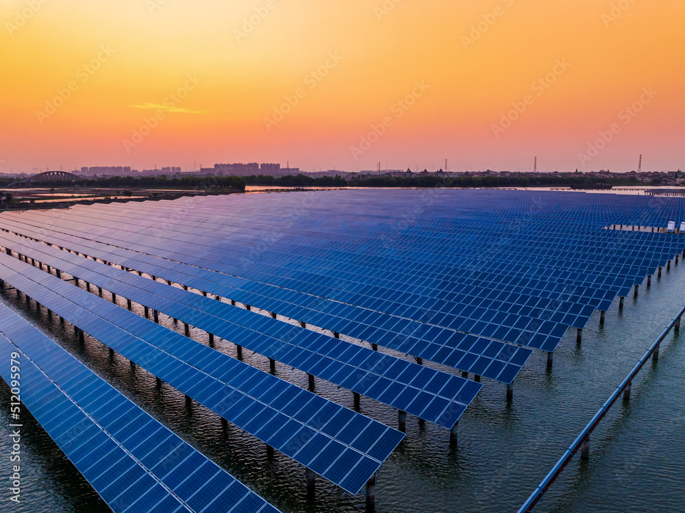 Fototapeta premium Aerial view of solar power station at beautiful sunset. solar photovoltaic power station on water. green energy concept.
