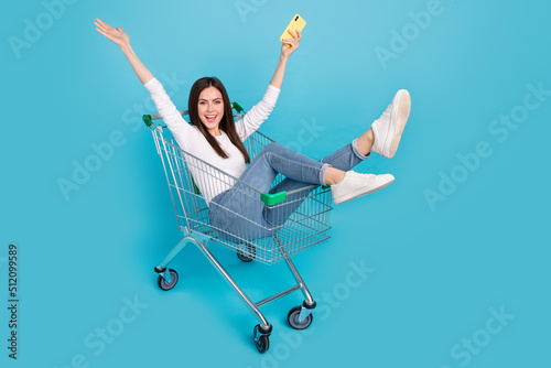 Photo of good mood overjoyed playful lady blogger influencer sit in pushcart isolated on blue color background