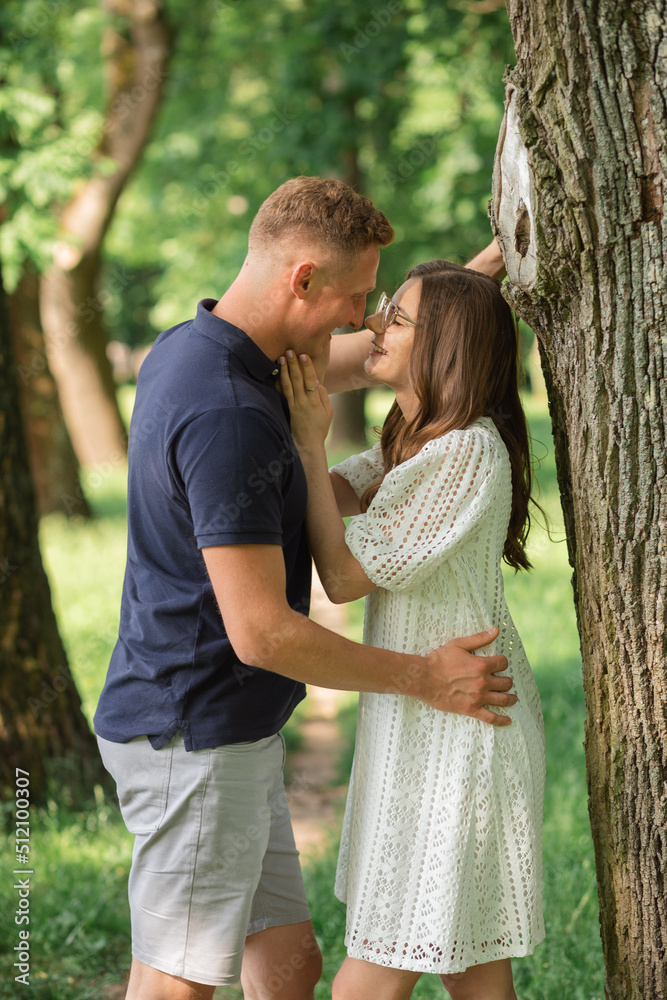 Fototapeta premium Portrait of lovely happy couple looking to each other at summer park, man embracing woman