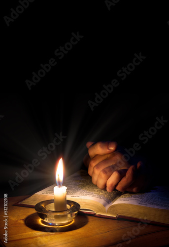 Hands folded in prayer over Scriptures