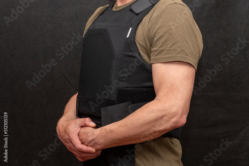 A muscular military man in a bulletproof vest on a black background. photo