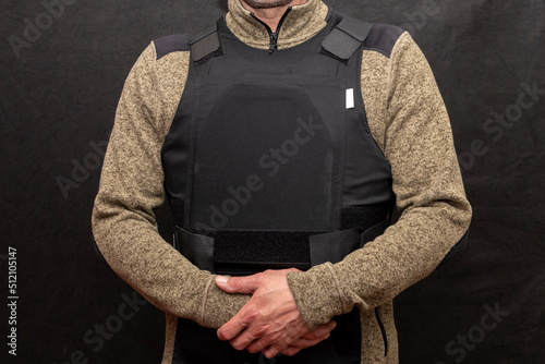 A muscular military man in a bulletproof vest on a black background. photo