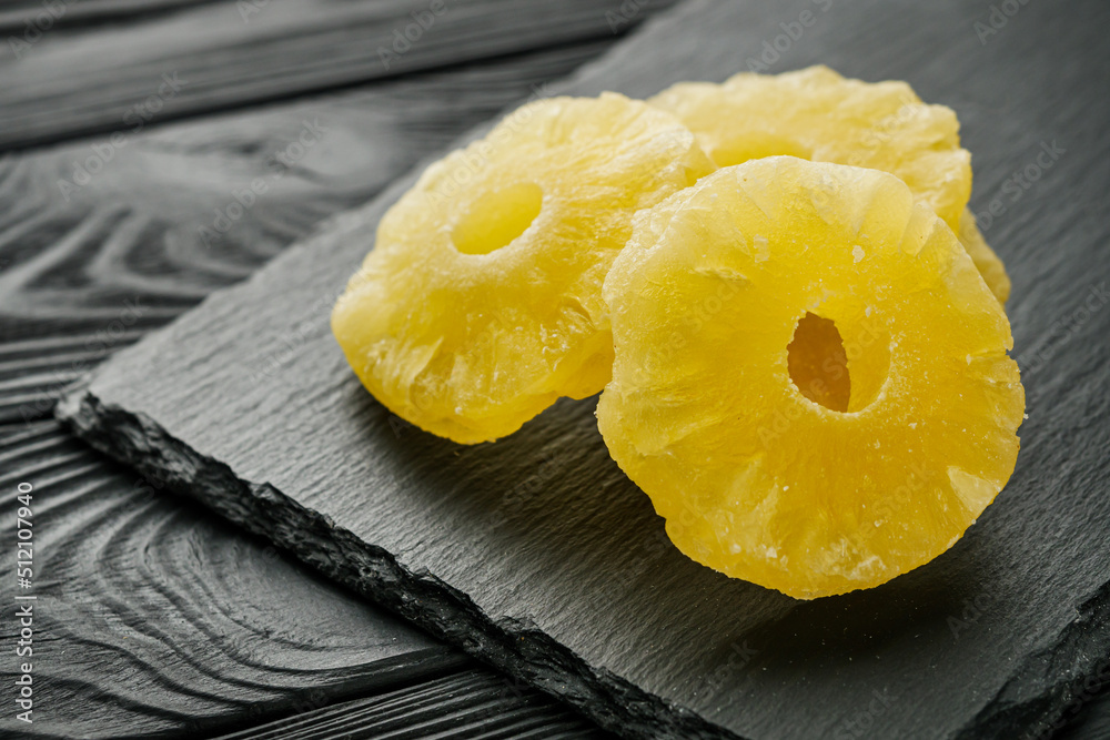 delicious dried pineapple on a black wooden rustic background delicious dried pineapple on a black wooden rustic background