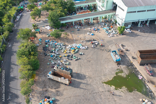 Aerial view of stack of different types of large garbage pile  plastic bags  and trash with a tractor car in industrial factory in environmental pollution. Waste disposal in dumping site.